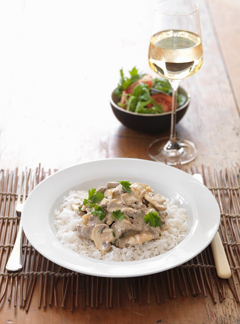 Boeuf stroganoff on a bed of rice with a glass of white wine