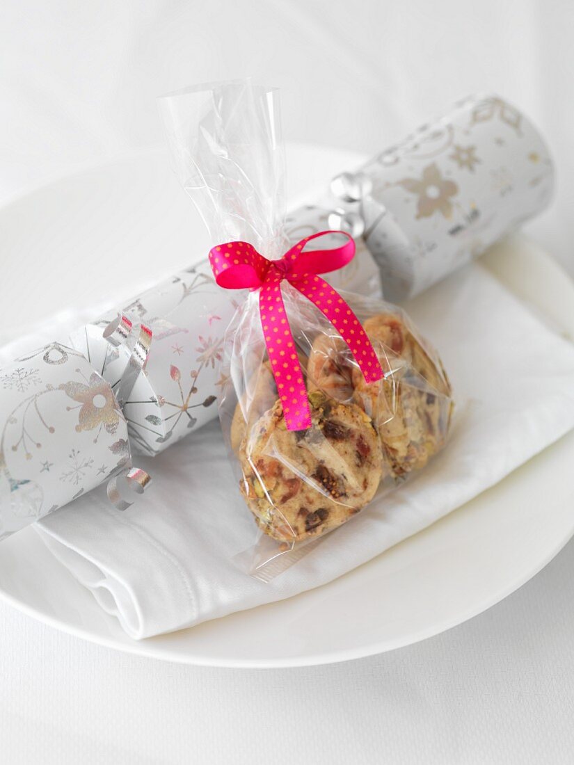 A Christmas cracker and a cellophane bag of biscuits on a plate