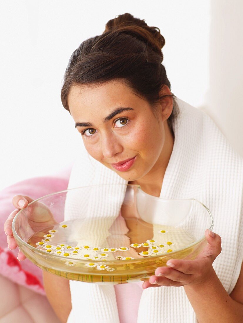 Woman holding bowl with camomile petals