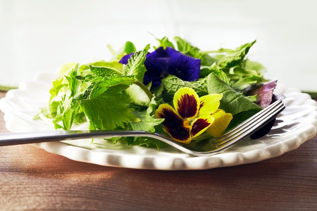 Mixed Green Salad with Edible Flowers on s White Plate