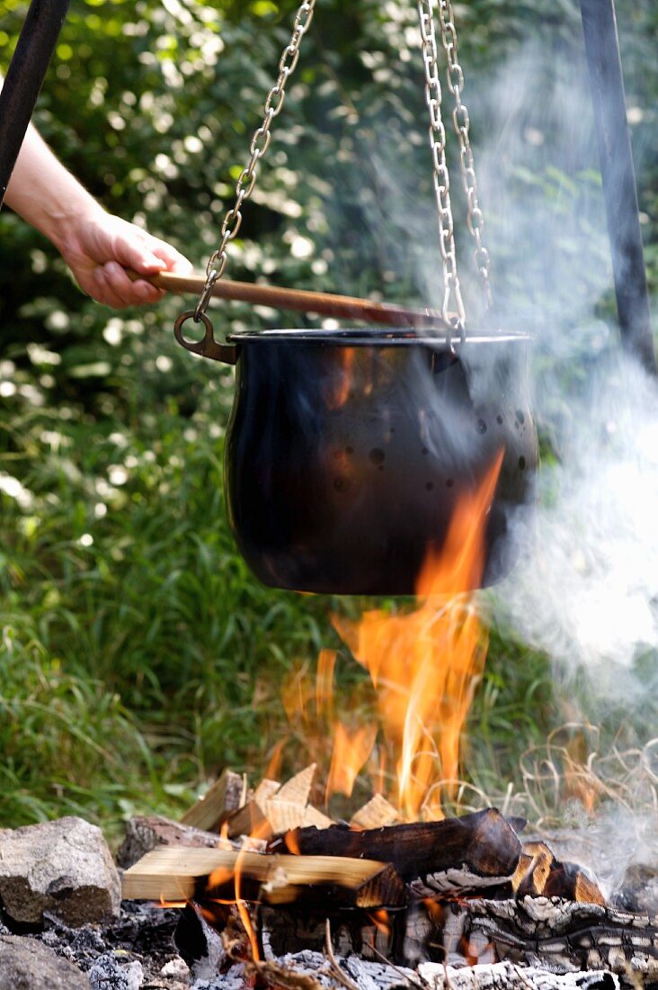 Vegetable soup in a cauldron over a camp fire