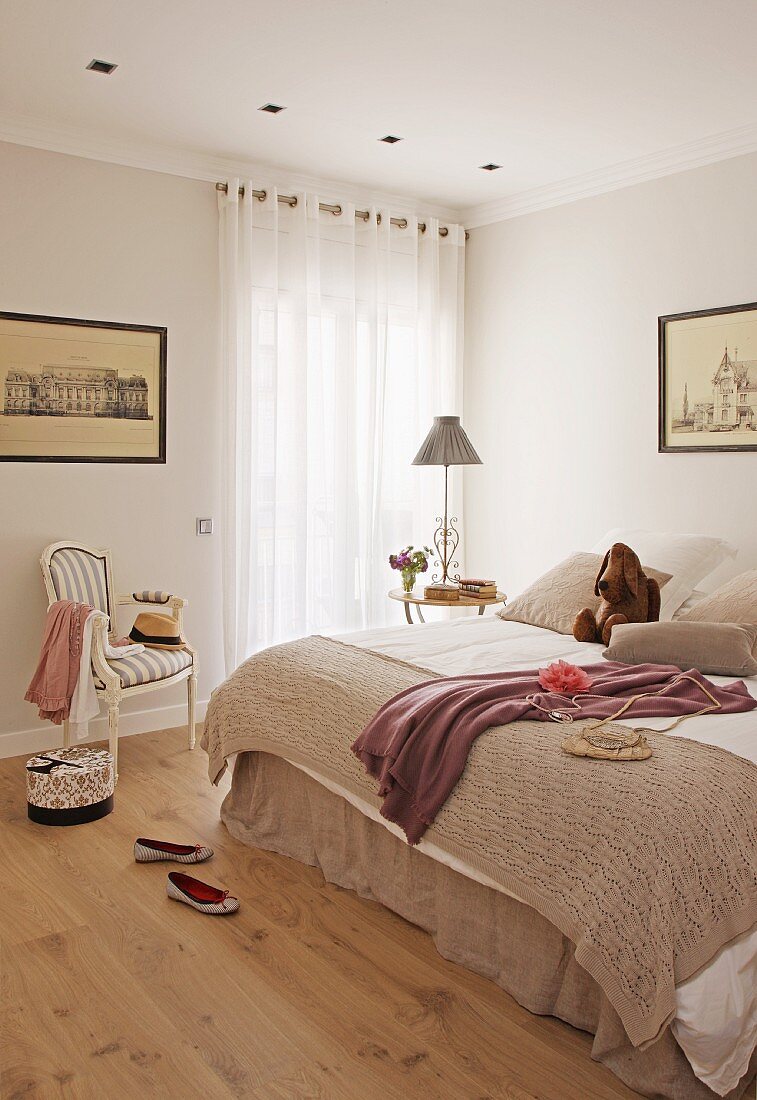 Simple bedroom with double bed and antique chair next to window with closed curtains