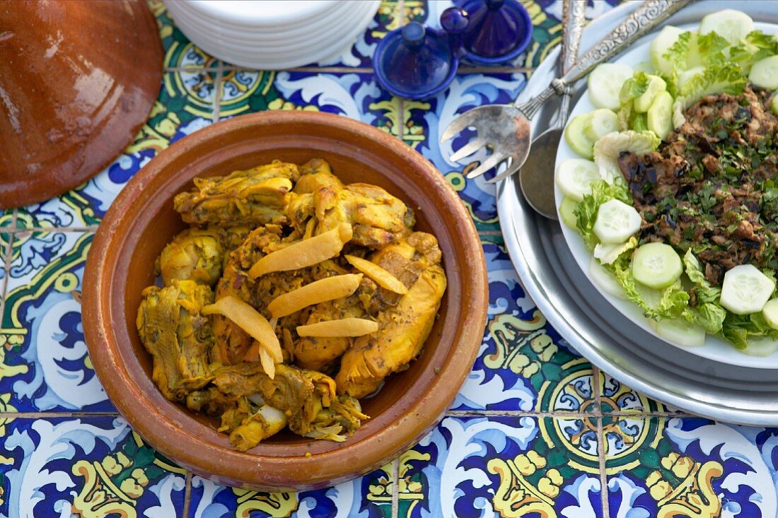 Chicken tagine and aubergine puree on table tiled with Oriental pattern