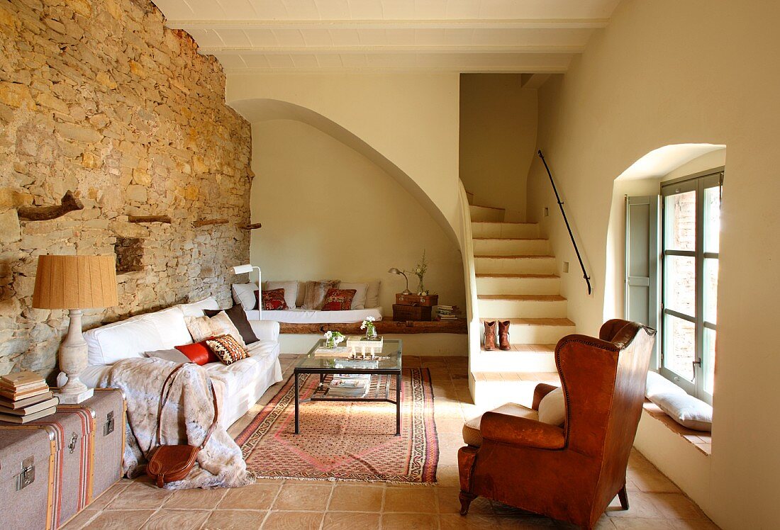 Leather wing-back chair in rustic interior with staircase