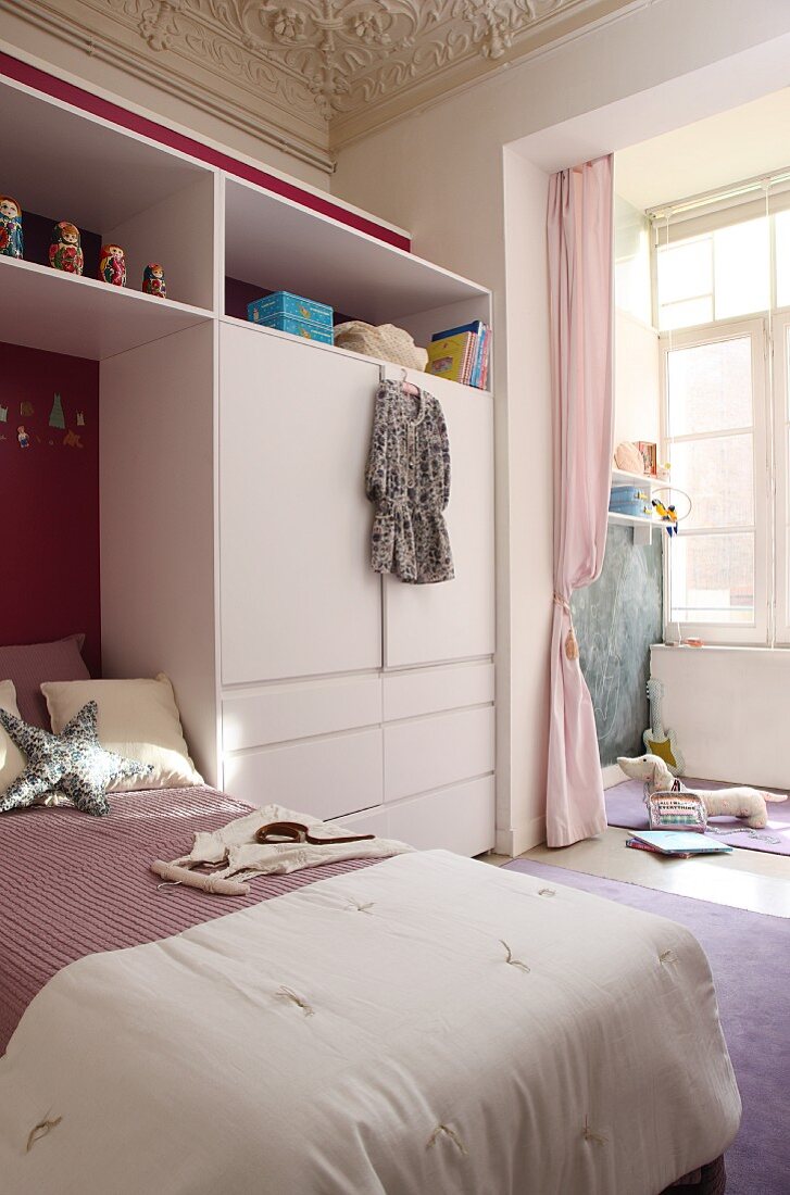 French bed integrated into white, modern fitted wardrobe; detail of stucco ceiling