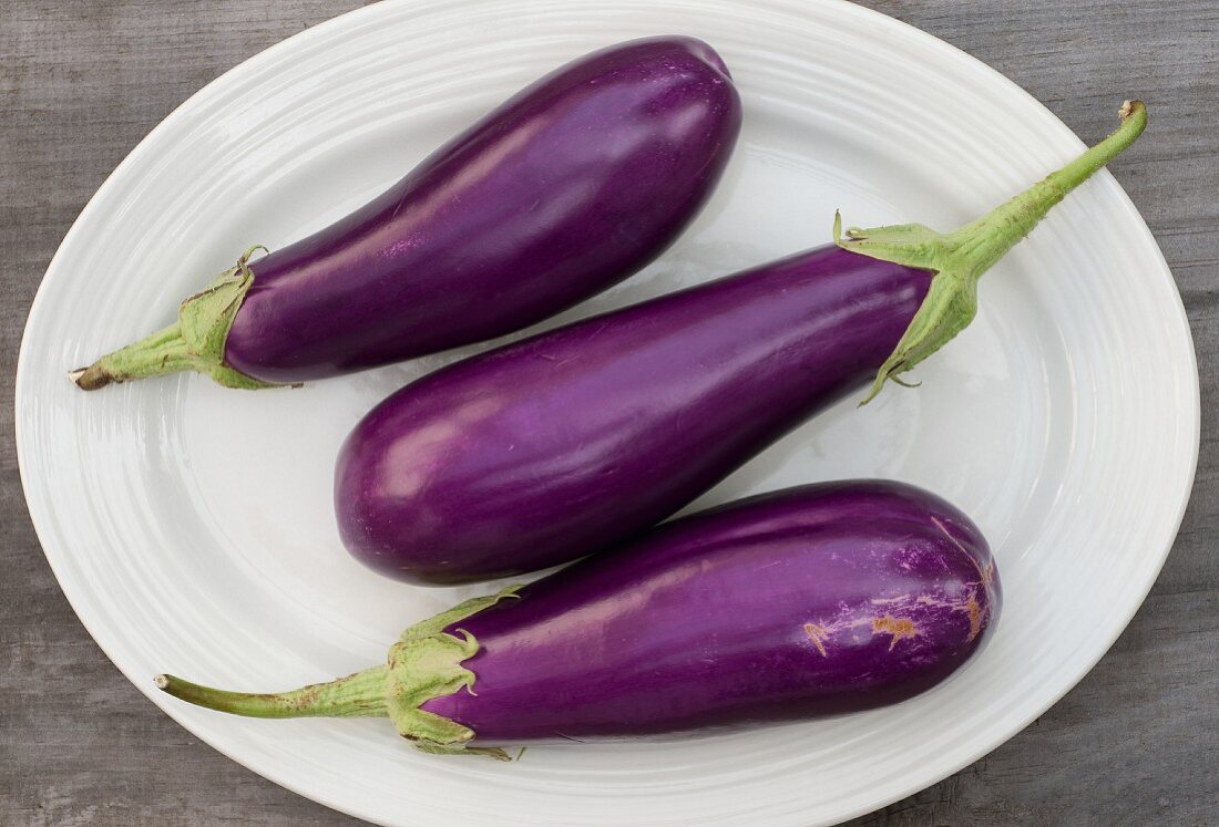 Three aubergines on white plate