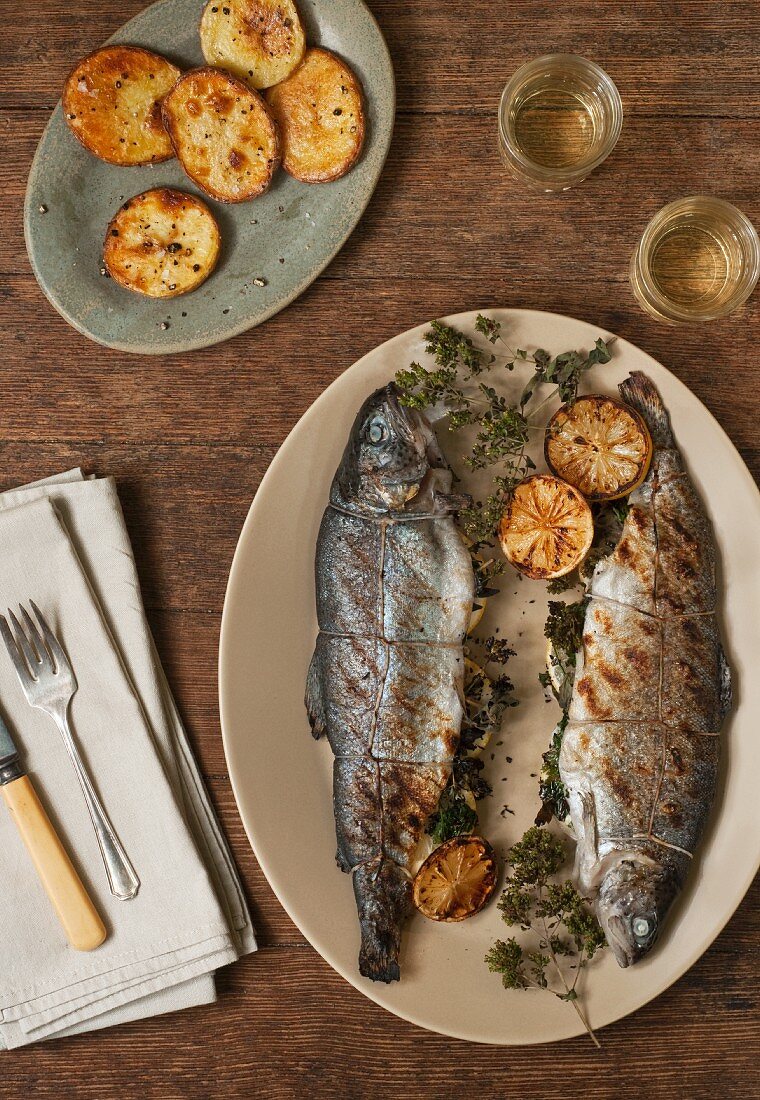 Grilled Trout Stuffed with Lemon and Parsley on a Platter; Oven Roasted Potatoes and White Wine