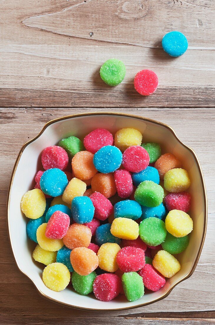 A Bowl of Colorful Gumdrops; Some on Table Next to Bowl