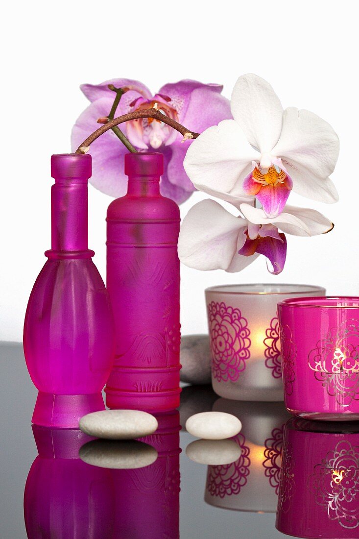 Hot pink bottles decorated with sprigs of orchids and tea light holders