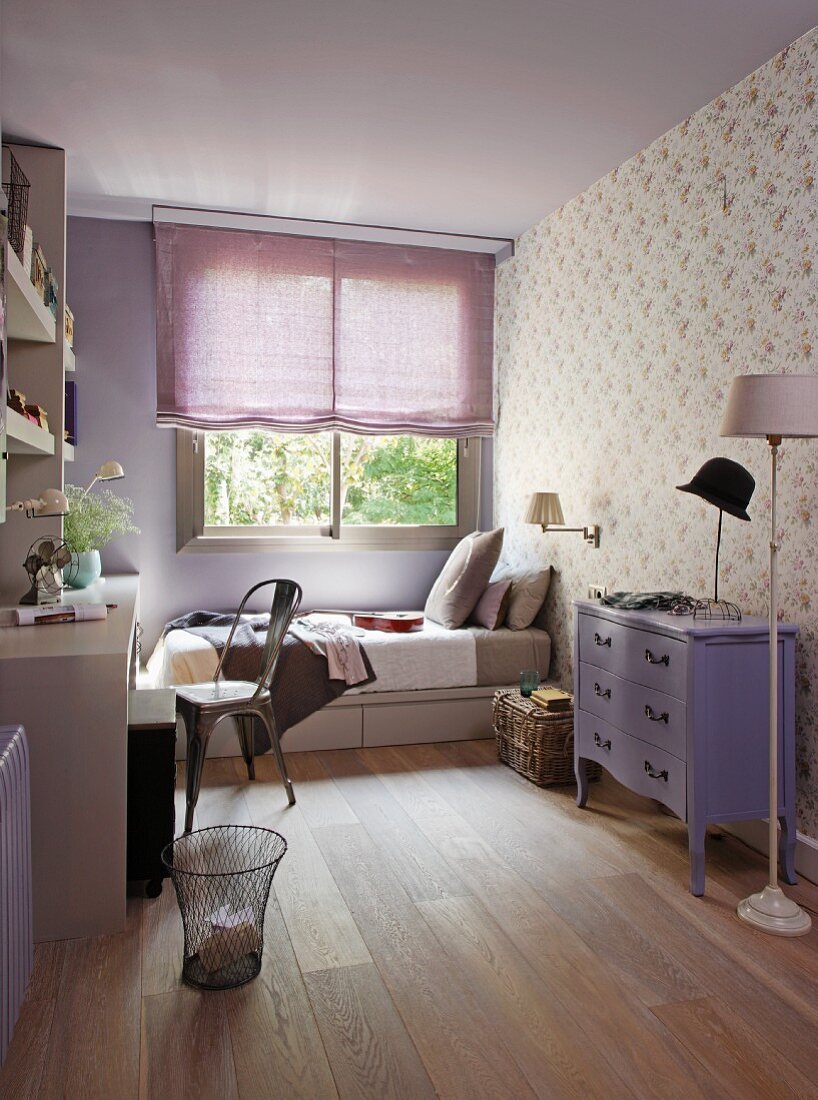 Lilac teenager's room - Neo-baroque chest of drawers painted purple against wall with patterned wallpaper and bed below window with half-closed blind