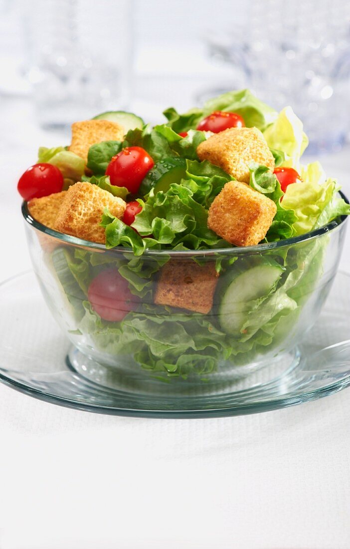 Salad with Croutons, Tomatoes and Cucumbers in a Glass Bowl