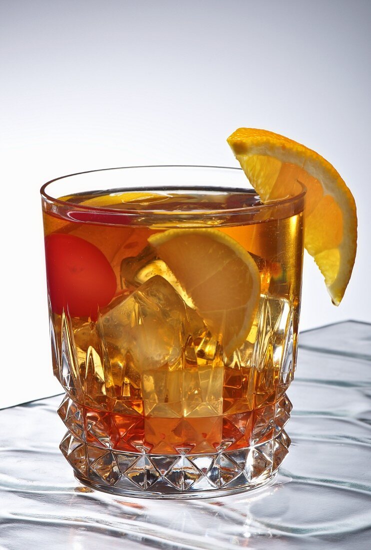 Classic Old Fashioned Cocktail in a Glass with Ice, Cherry and an Orange Wedge Garnish