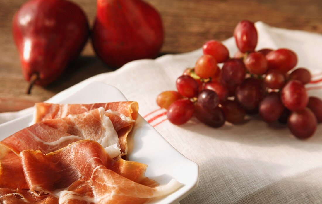 Stillleben mit Prosciutto, roten Trauben & Birnen
