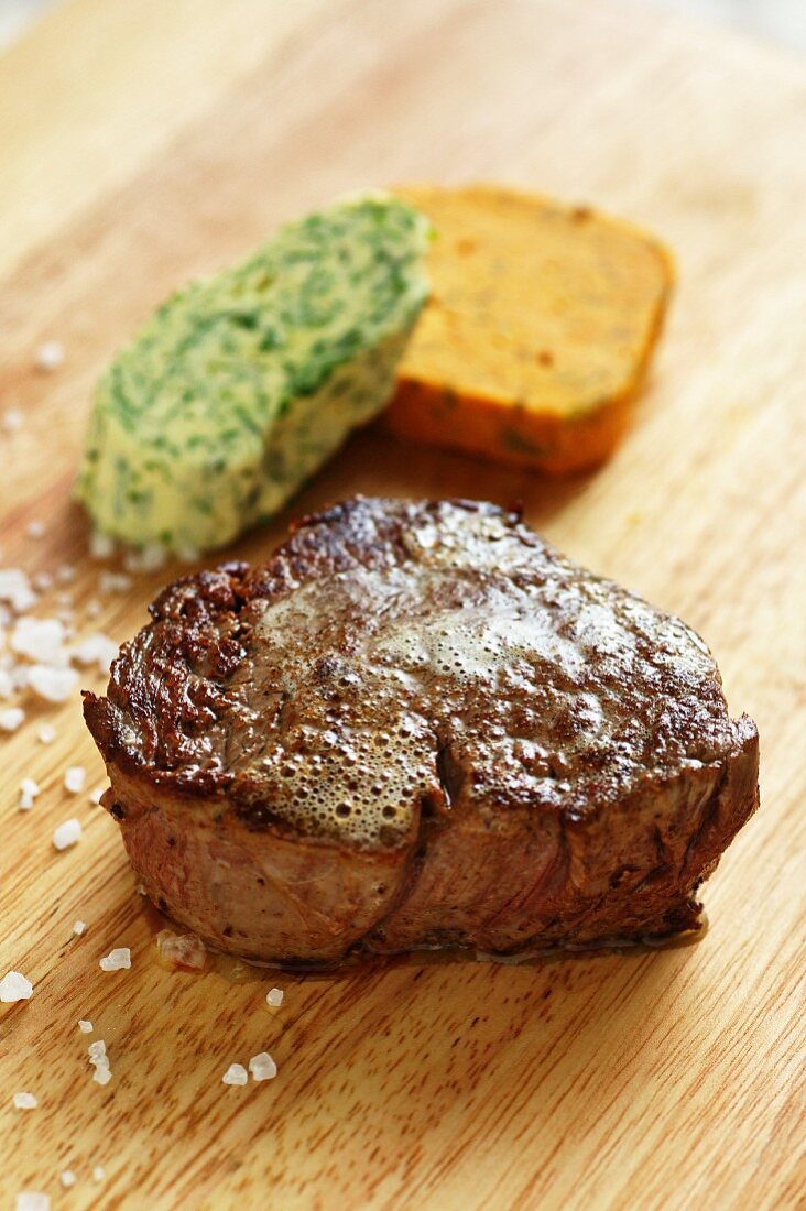 Beef steak with herbs and pepper butter on a wooden board