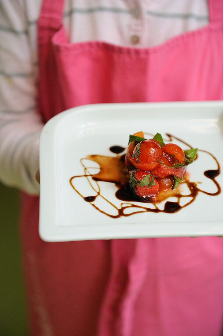 A person serving strawberry and tomato tartar with balsamic vinegar