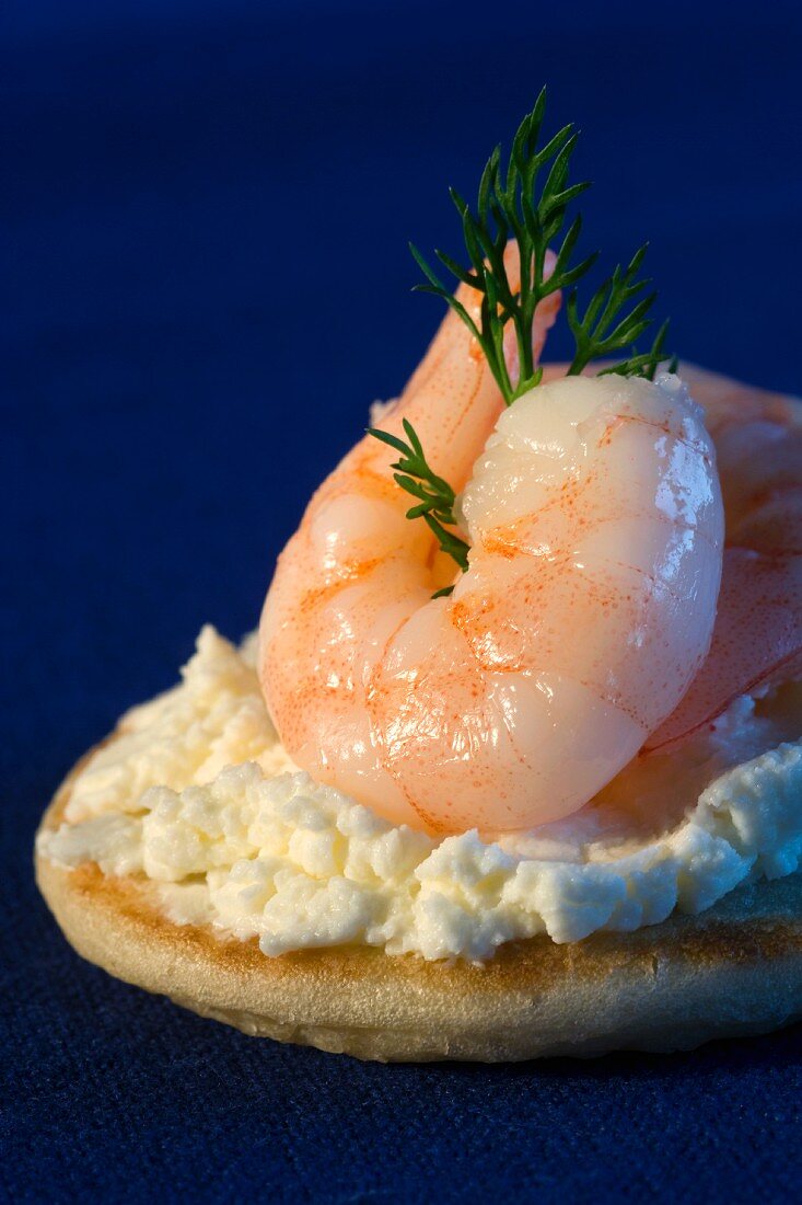 A blini topped with cream cheese and prawns