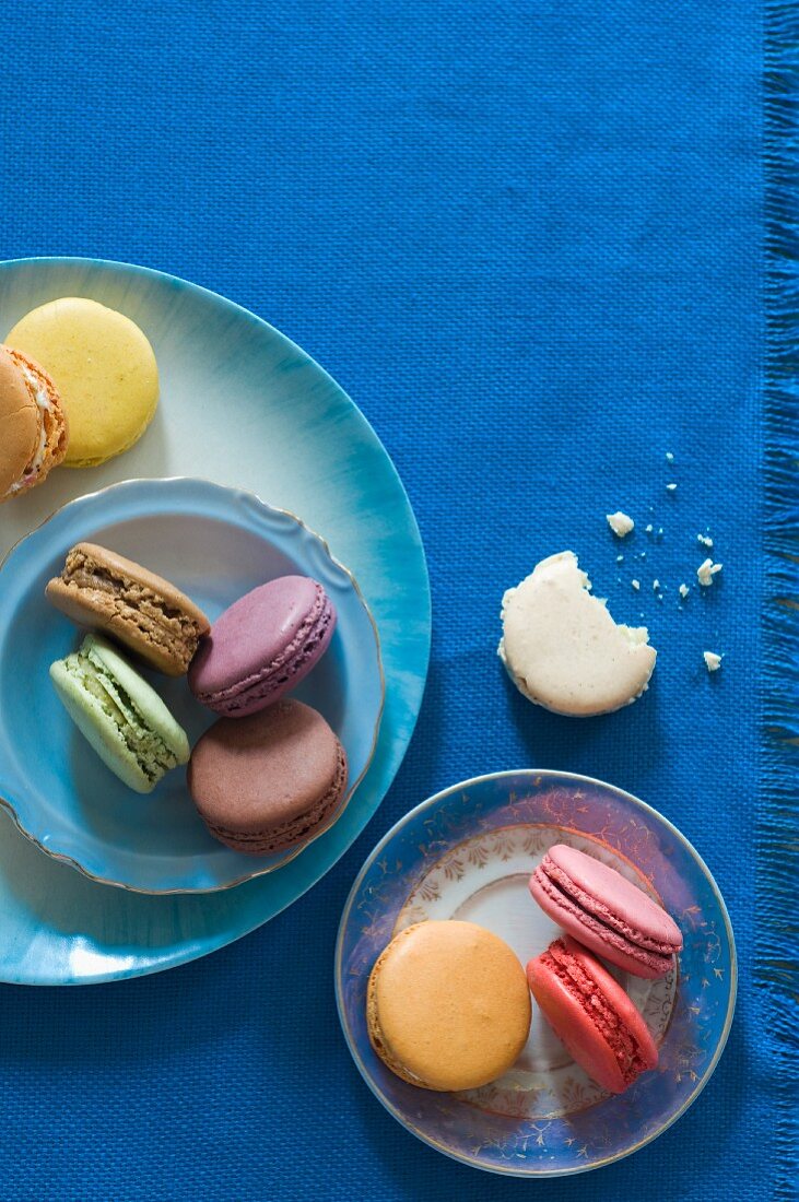 Colorful Macaroons on Plates; From Above; One with a Bite Taken Out