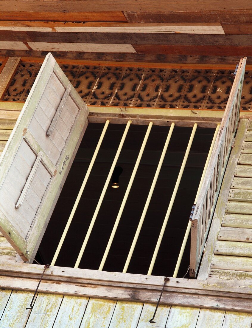 Open shutter at barred window of traditional Oriental wooden house