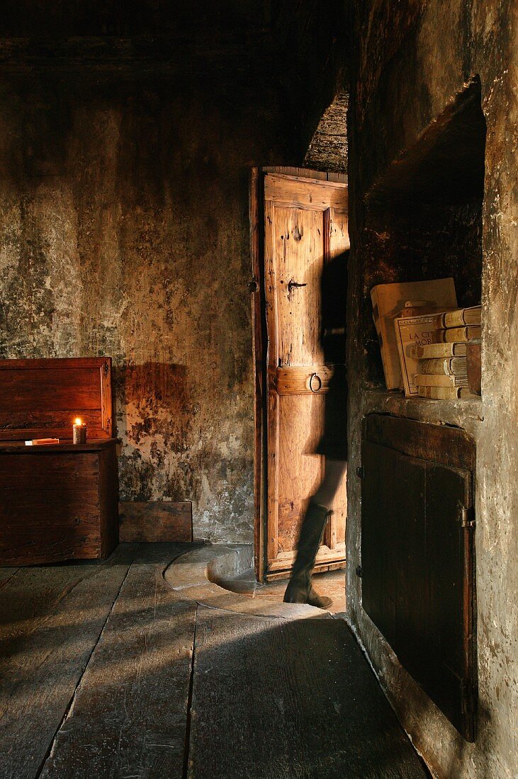 Gestalt in halboffener Tür eines alten Zimmers mit verrussten Wänden