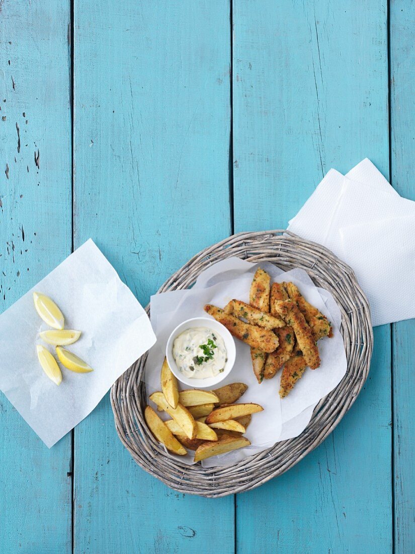 Fish fillets with a parmesan and lemon coating a potato wedges (seen from above)