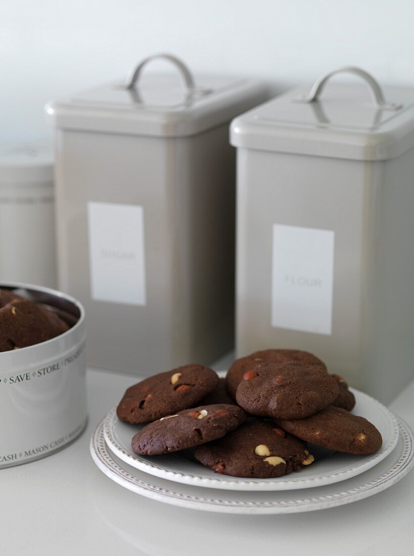 Chocolate biscuits with peanuts and storage tins in the background