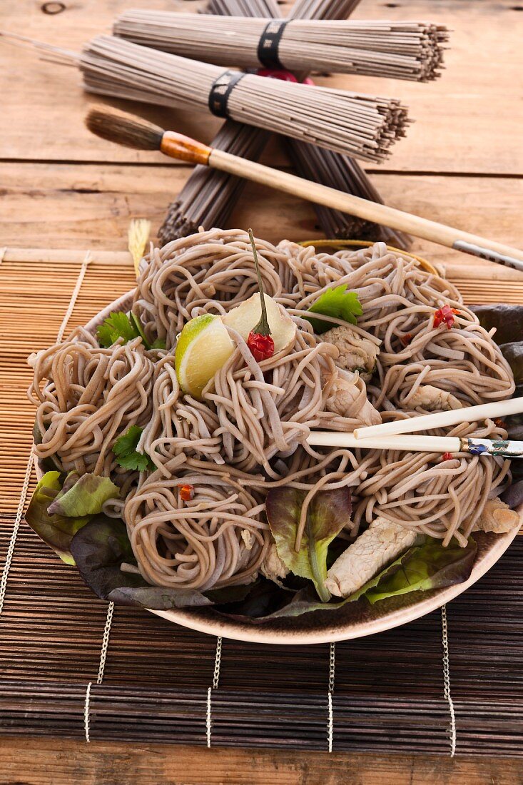 Soba noodle with chicken breast strips, mixed leaf salad, chilli oil and limes