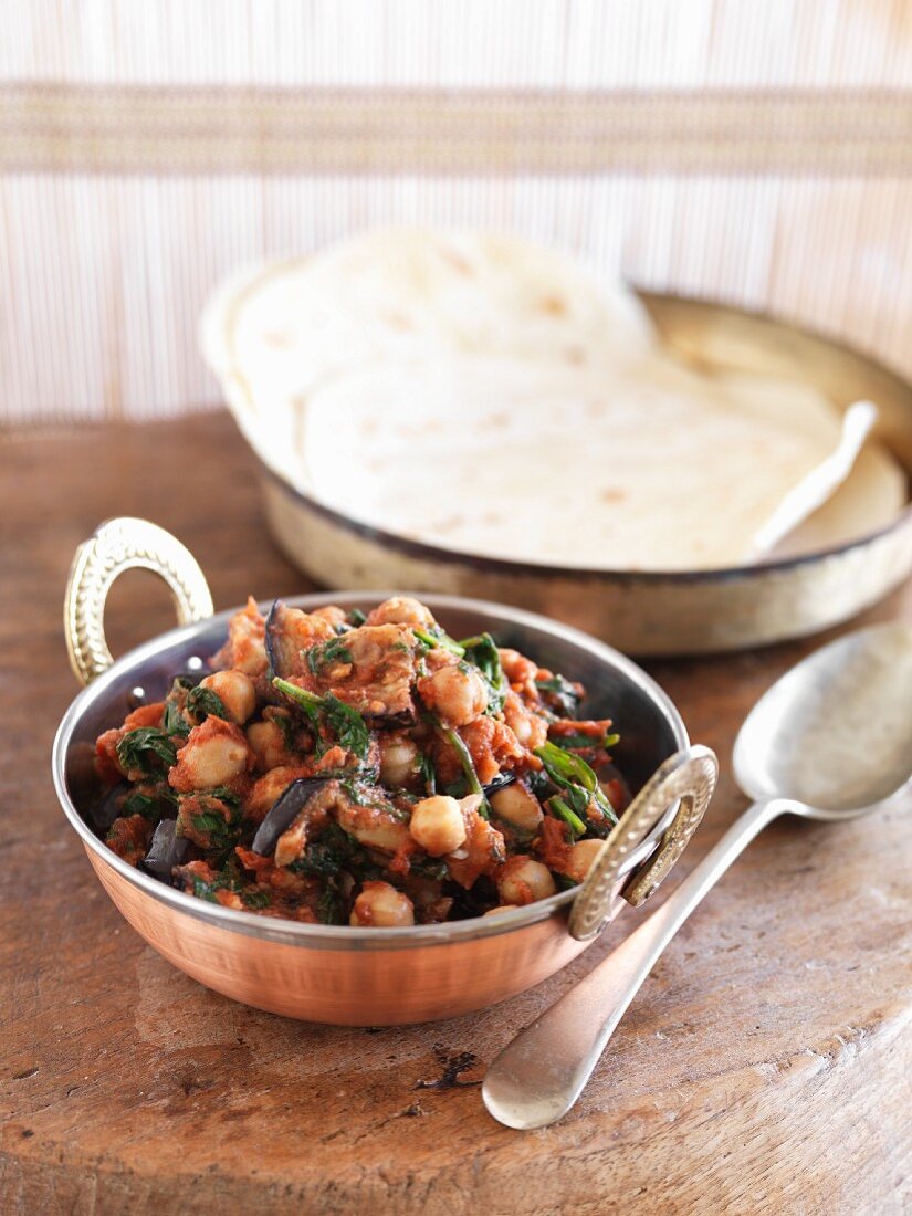 Chickpea curry with aubergines and spinach served with unleavened bread