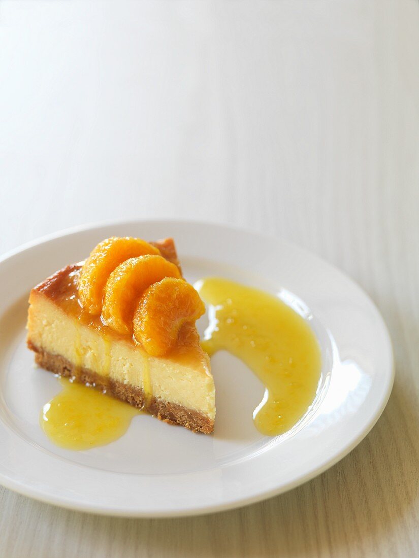 A slice of cheese cake with mandarins