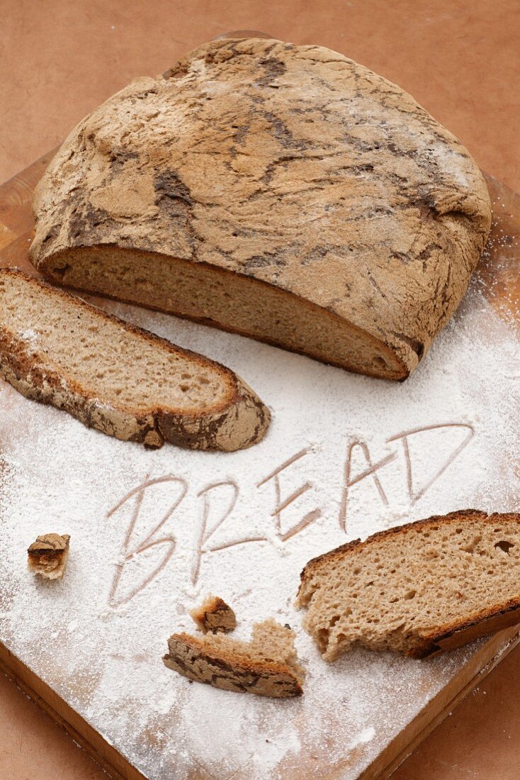 Country bread, sliced and the word BREAD written in flour