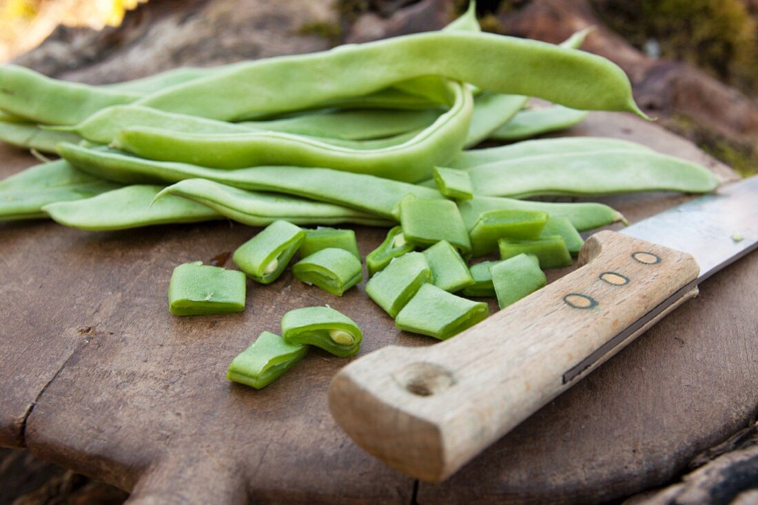 Fresh green beans with a knife on a chopping board