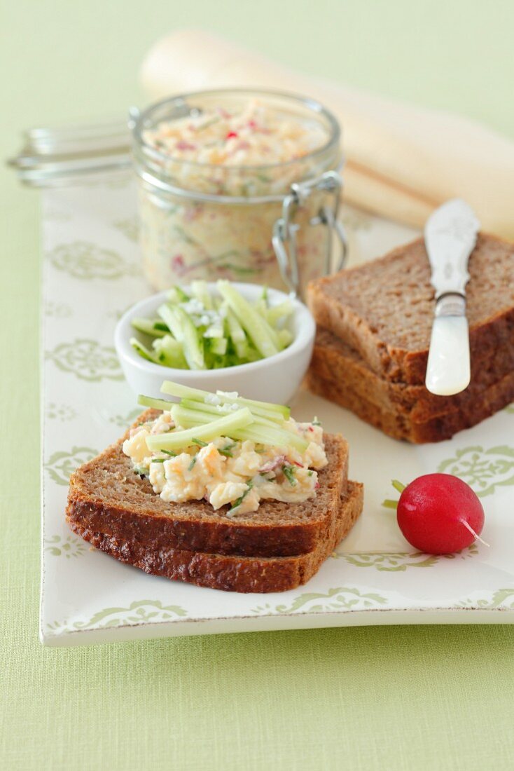 Egg salad spread with radishes, cucumber and herbs on wholemeal bread