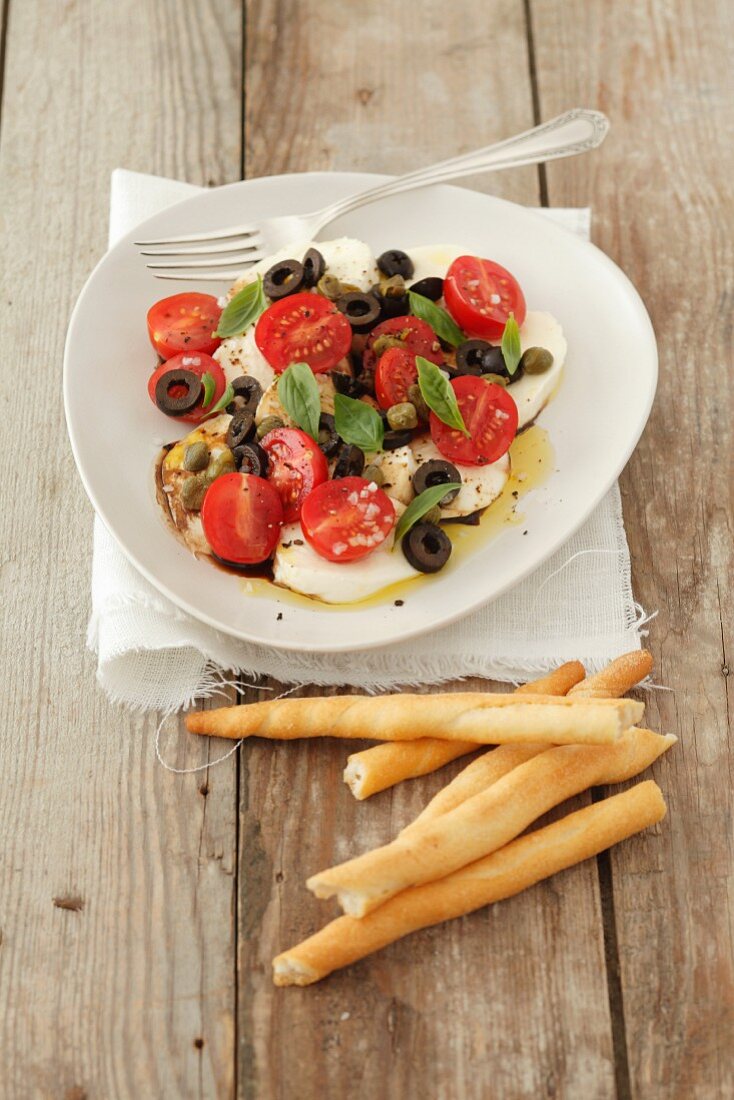 Cherry tomatoes with mozzarella, olives, capers and basil