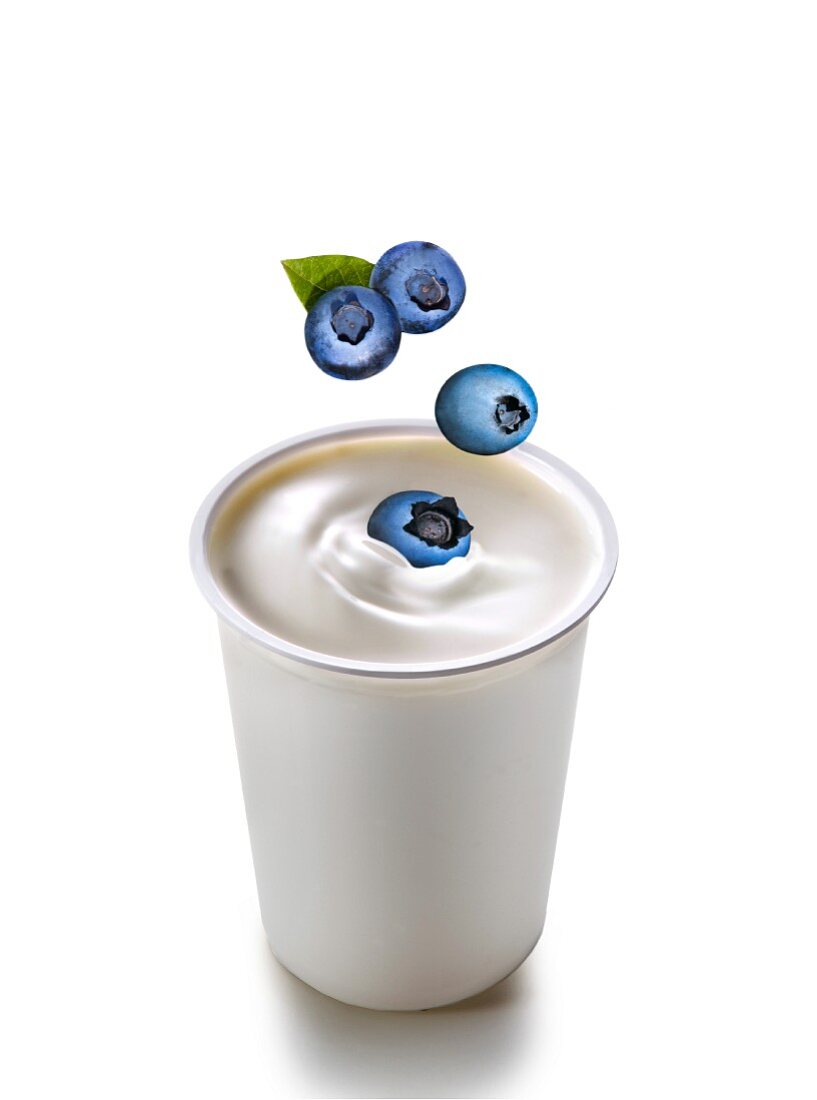 Blueberries falling into yogurt