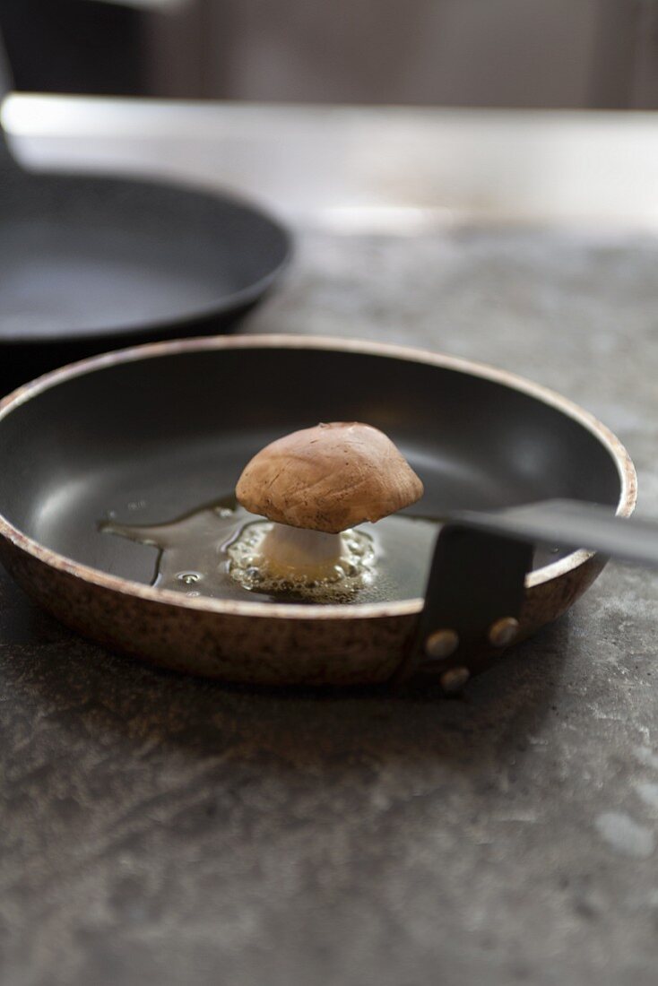 A porcini mushroom being fried in a pan