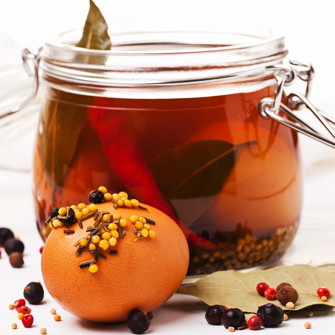 Pickled eggs, preserved in brine and spices, in a jar and in front of it