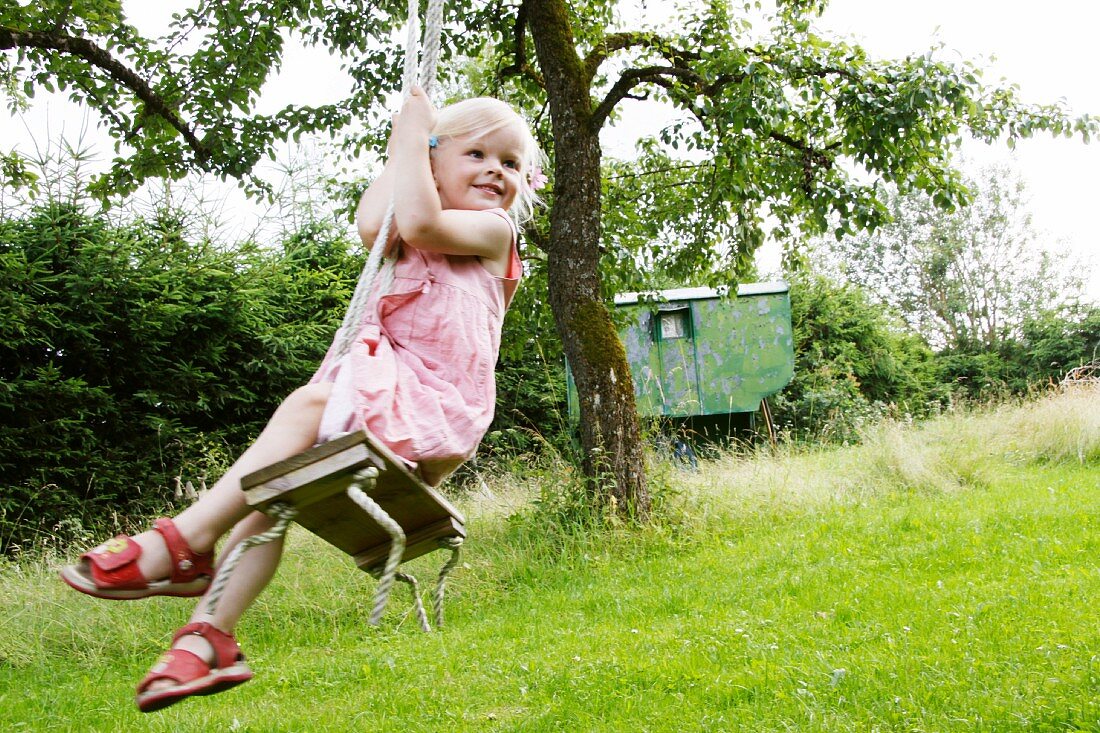 Blond girl on a garden swing