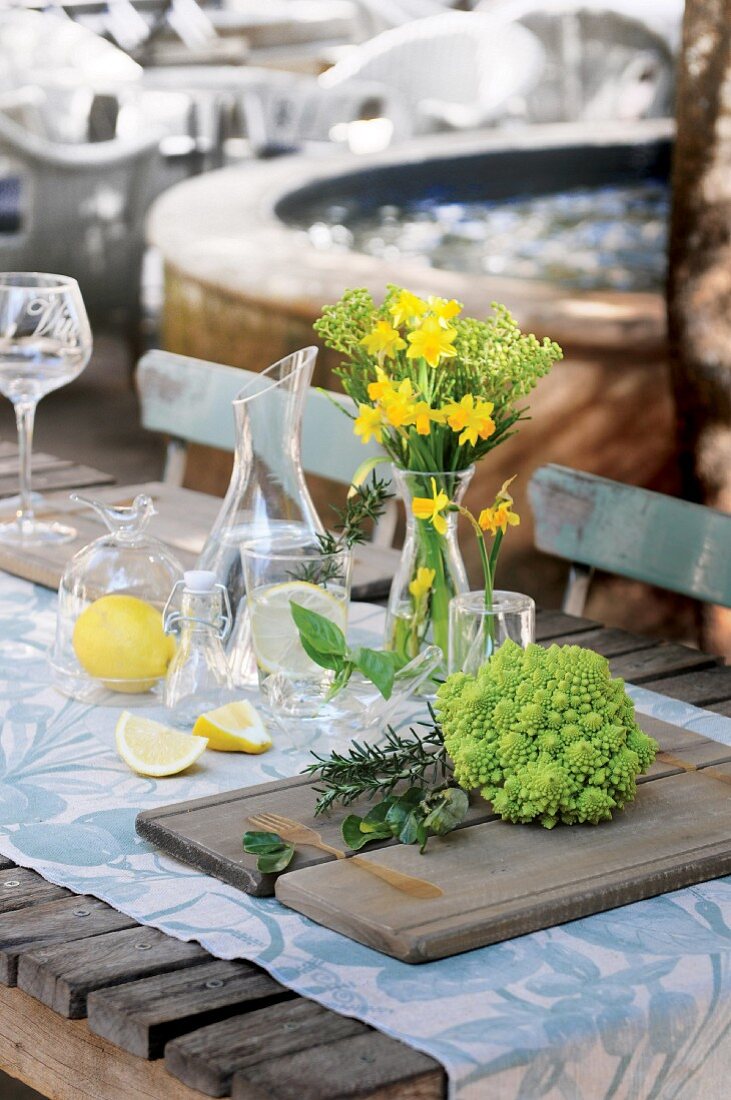 Gedeckter Tisch mit Tischläufer, Blumenstrauss, Romanesco und Zitronen