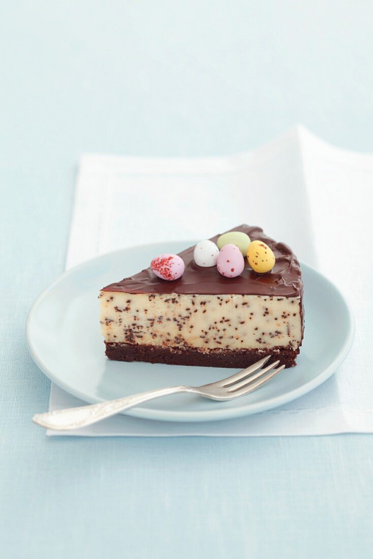 A slice of cheesecake with chocolate chips, chocolate glaze and sugar eggs