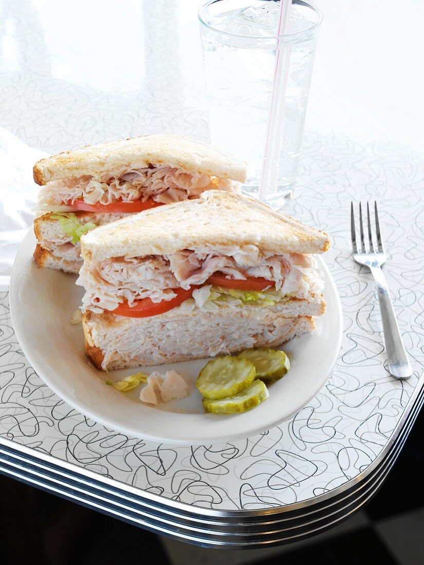 Double Decker Turkey Sandwich with Kosher Pickles on a Plate