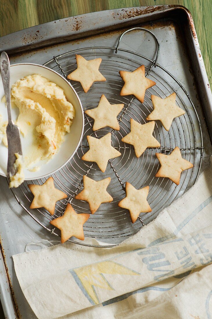 Freshly Baked Star Shaped Cookies on a Cooling Rack; Bowl of Frosting