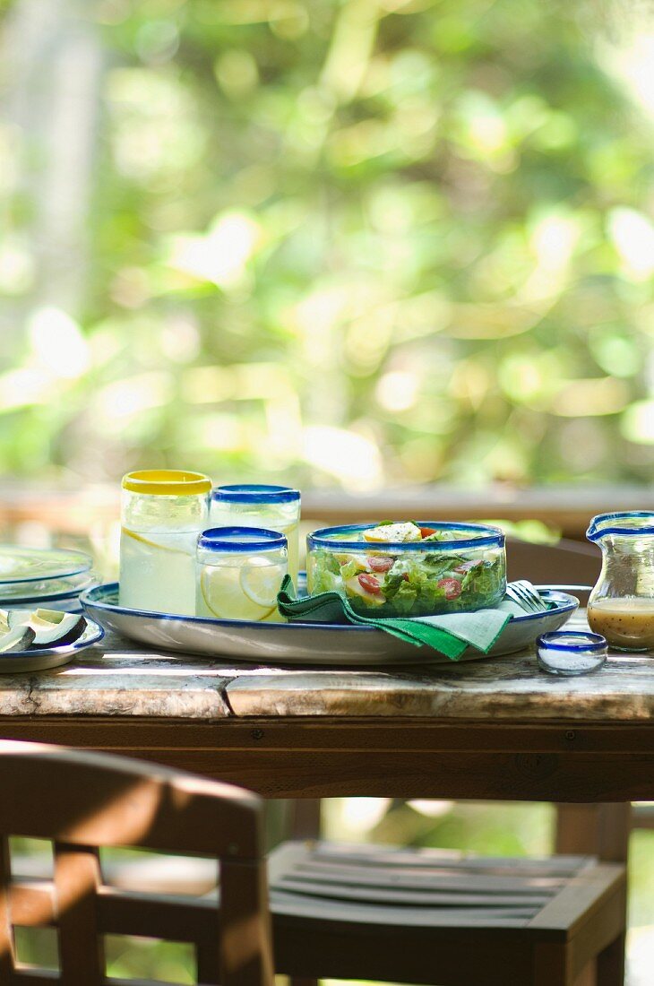 Glasses of Lemonade and Salad in a Glass Bowl on an Outdoor Table