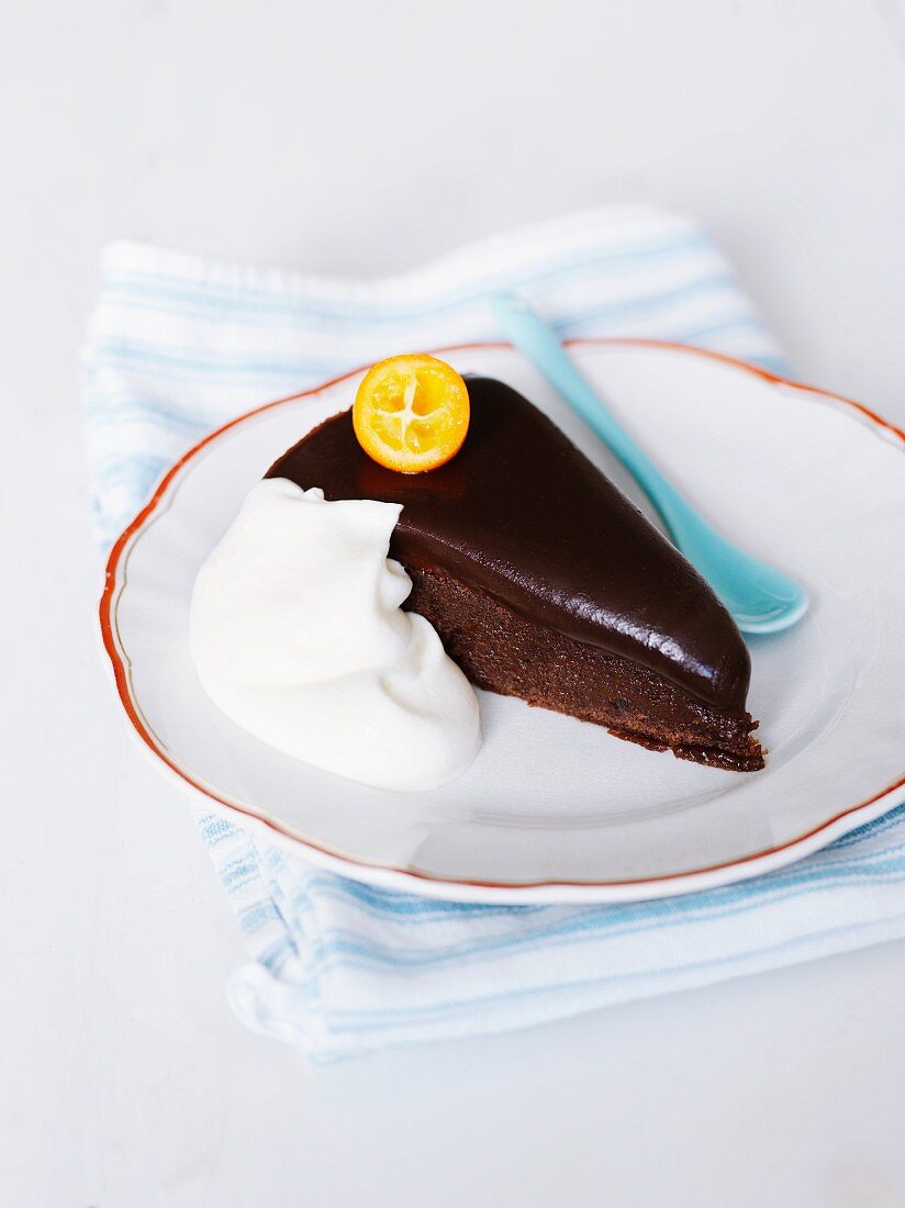 A slice of chocolate cake topped with a kumquat