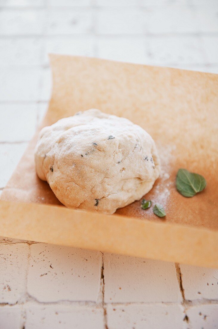 Pizza dough with herbs on a piece of baking paper