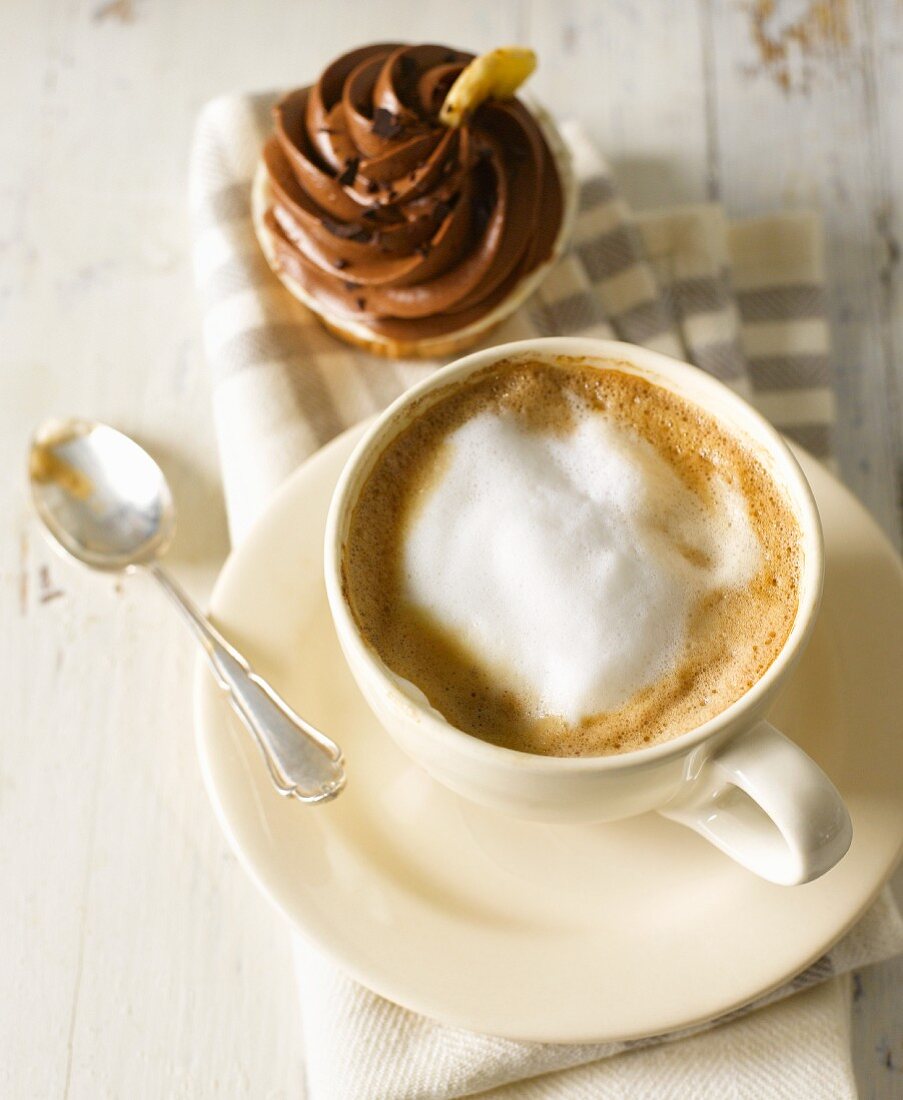 Eine Tasse Cappuccino mit Schokoladen-Cupcake