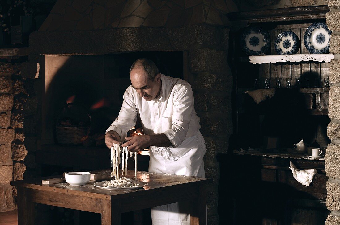 Cook handling pasta dough in kitchen