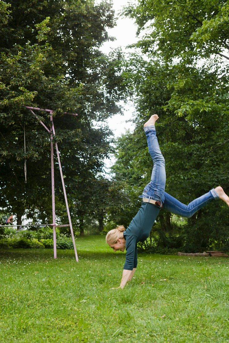 Frau macht Handstand im Garten