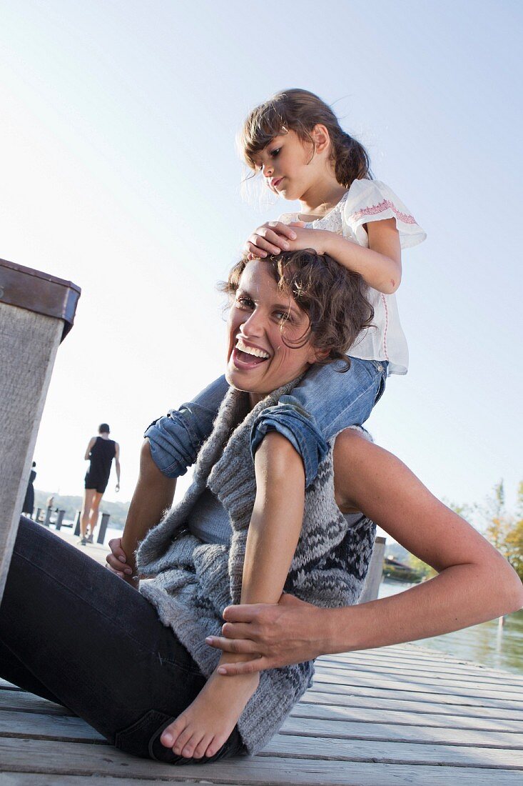 Mother and daughter sitting on pier