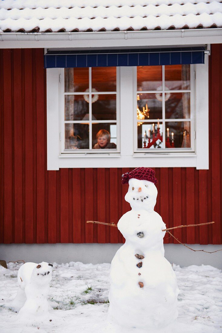 Snowmen standing outside house