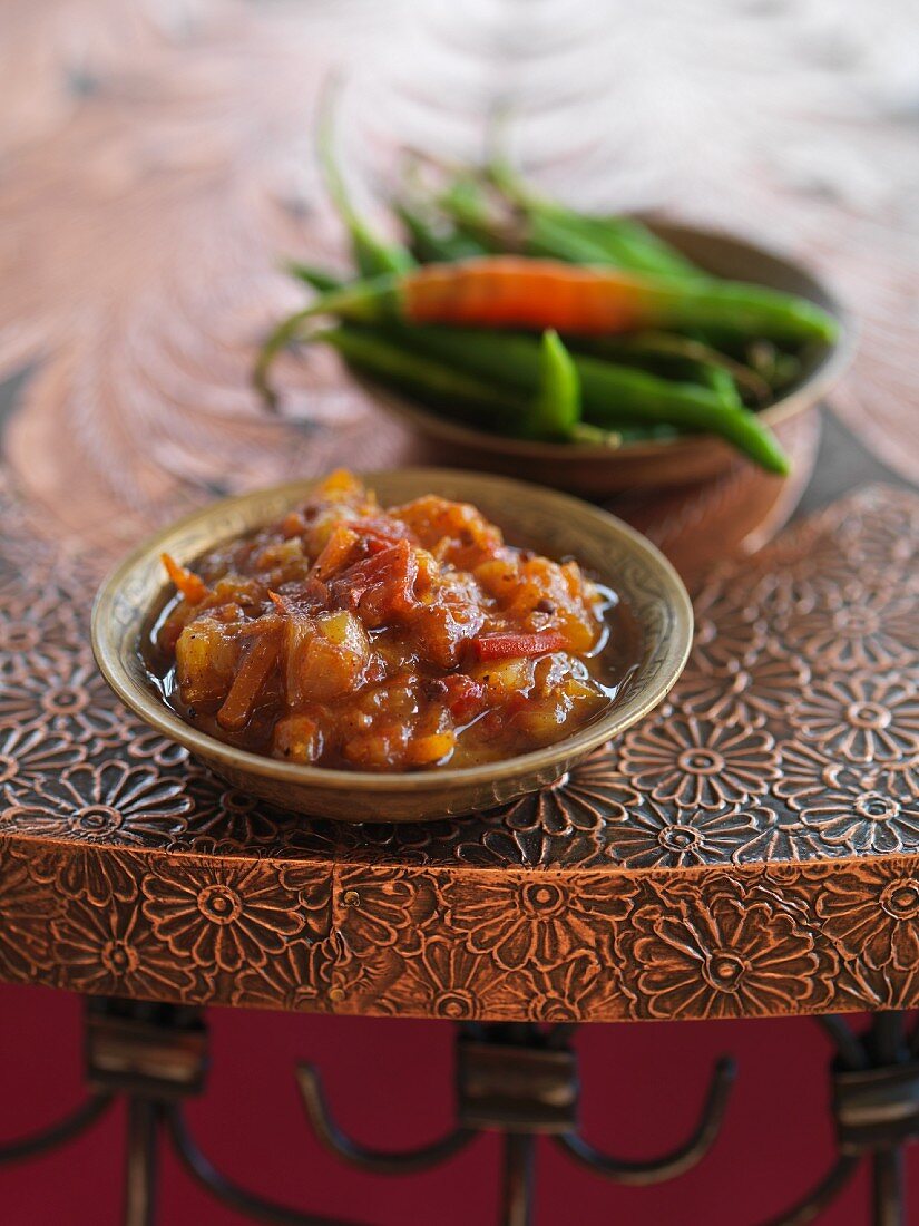 Indisches Chutney, im Hintergrund Schale mit Chilis