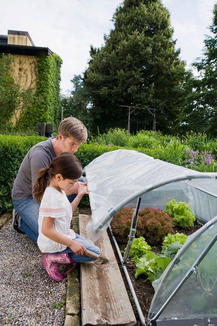 A father and daughter at a greenhouse in a garden